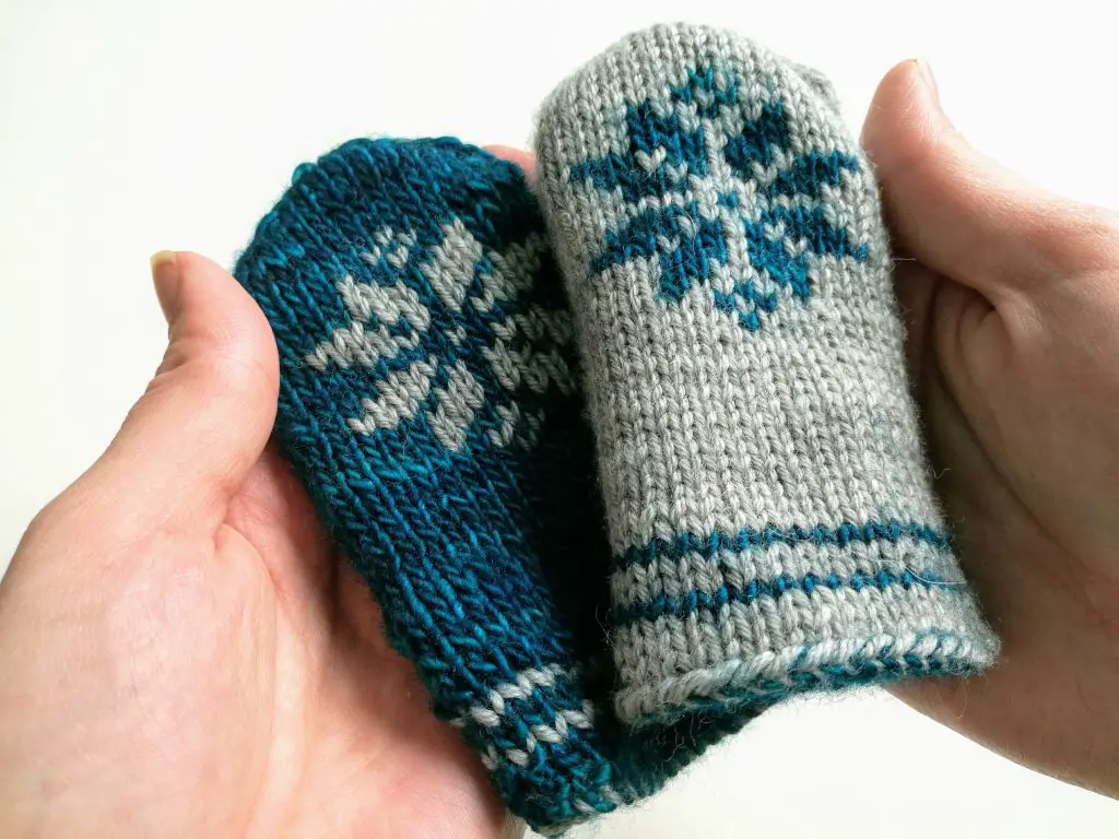Thumbless baby mittens with a snowflake motif.